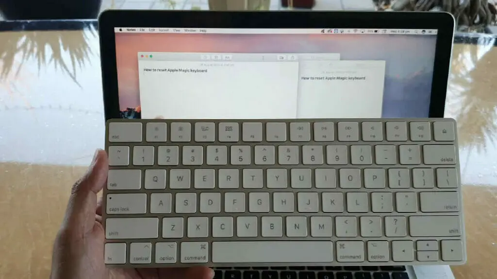 a left hand holding a white wireless keyboard