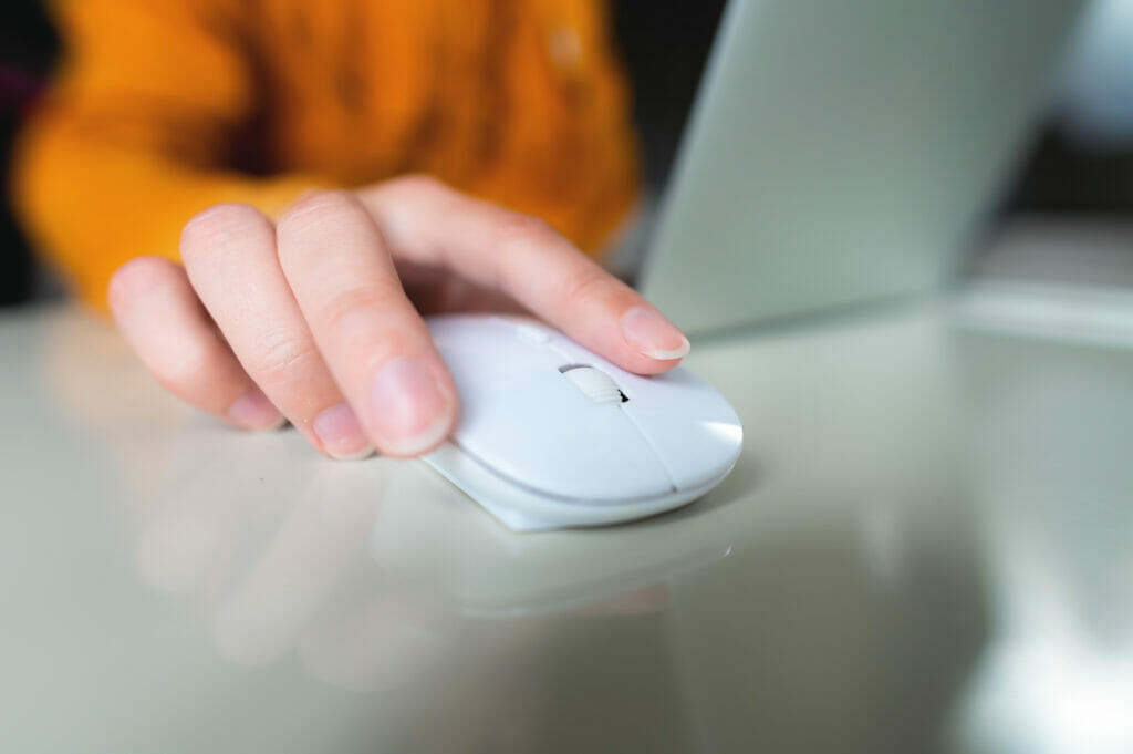 a woman's right hand working with a white wireless mouse