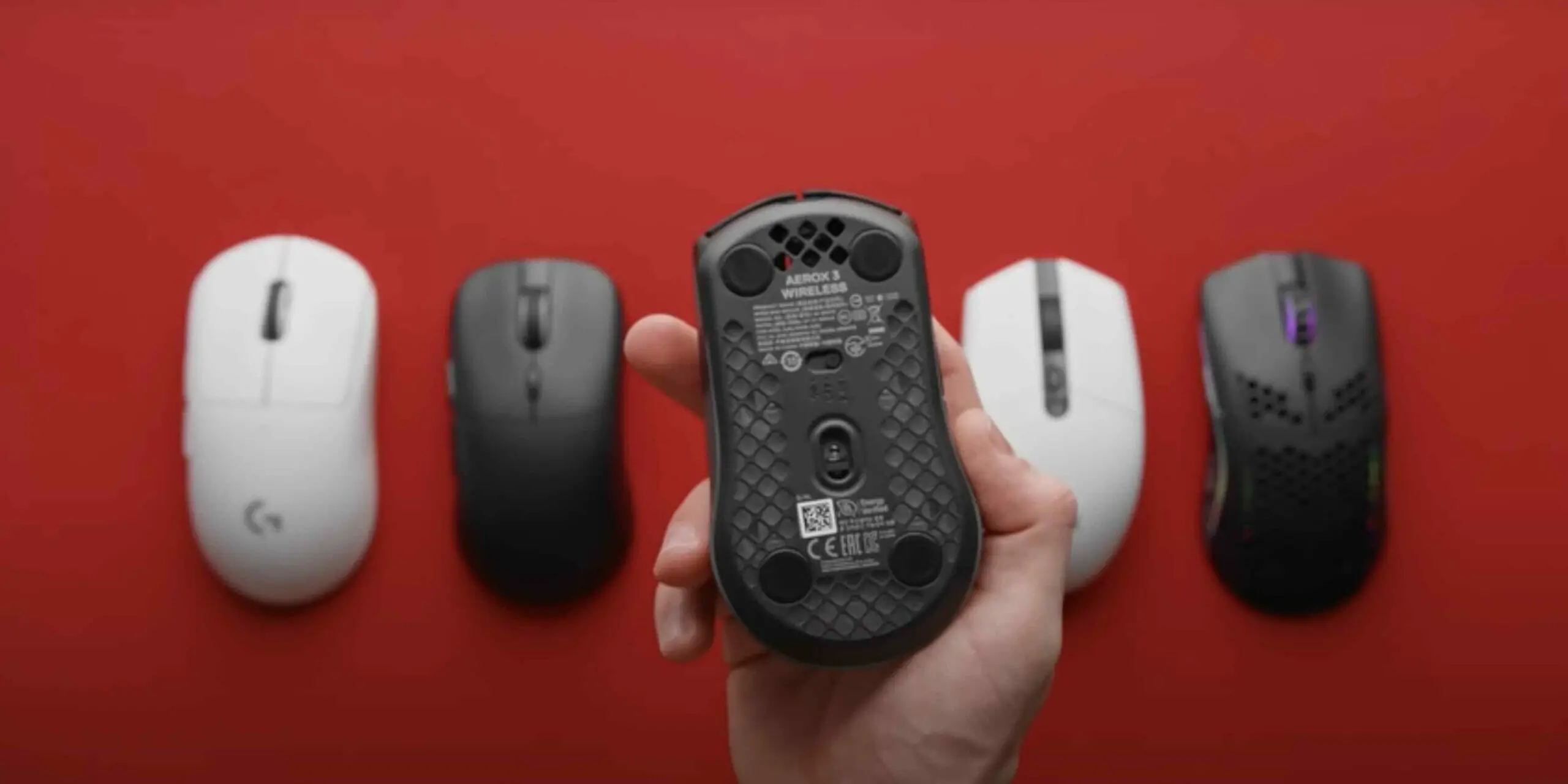 group of wireless mouse in a red background and 1 mouse is being held by a man's hand