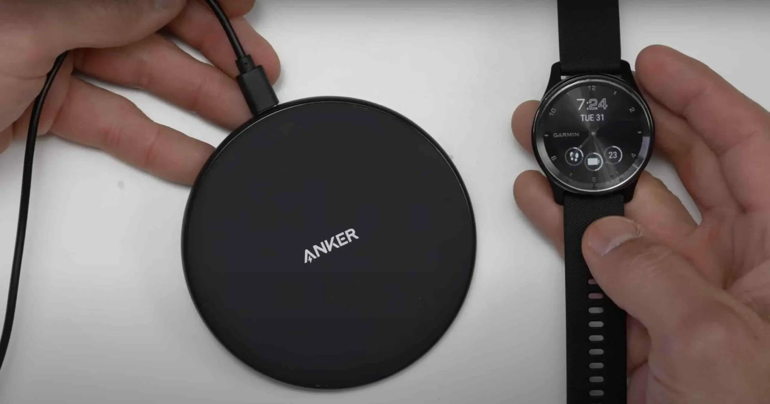 man holding an anker wireless charger and a garmin watch