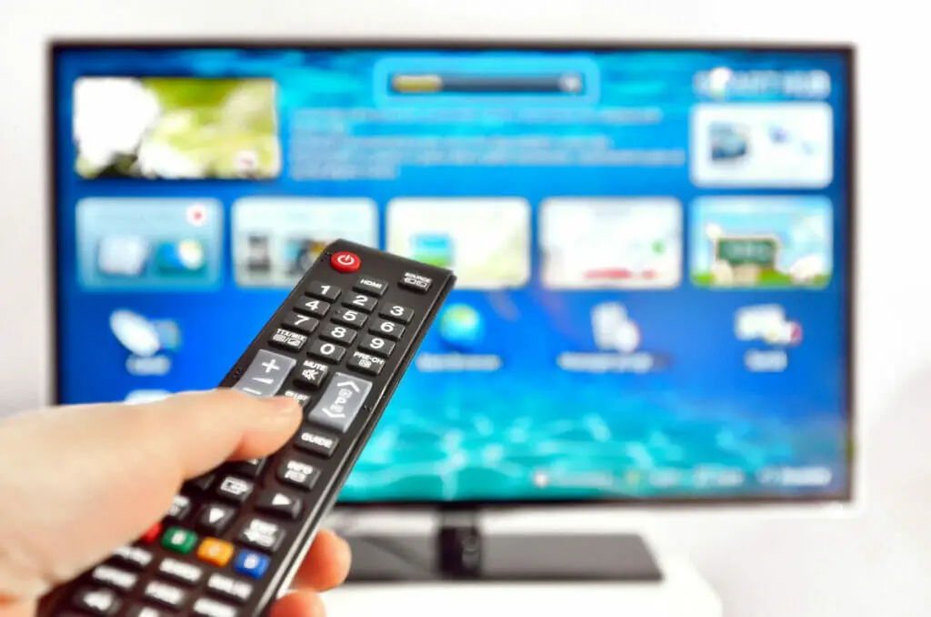 man pressing the remote control of his smart tv
