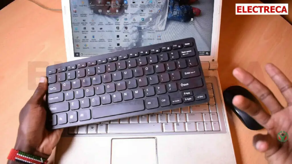 man's hand holding a black wireless keyboard