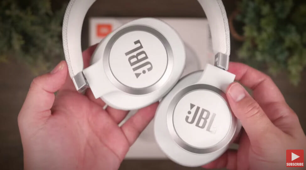 man's hand holding a while JBL headphone