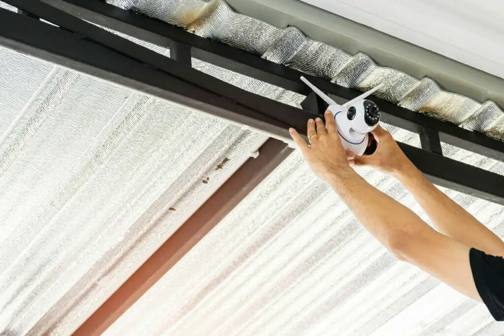 technician installing a wireless security camera at the outdoor ceiling