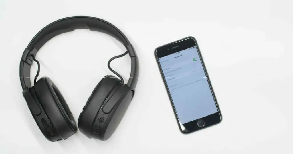 top shot of a black wireless headphone beside a phone for pairing