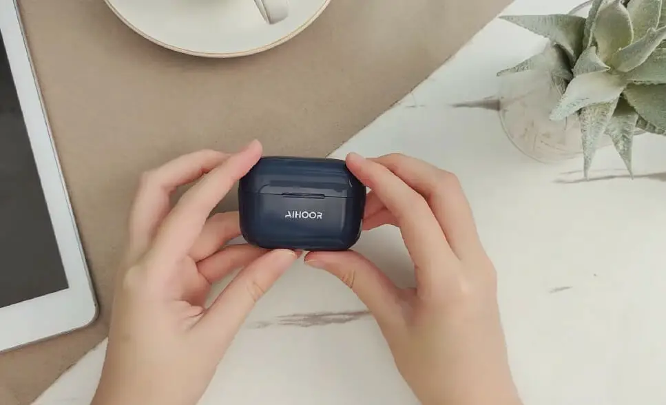 woman's hands holding an AIHOOR earbuds