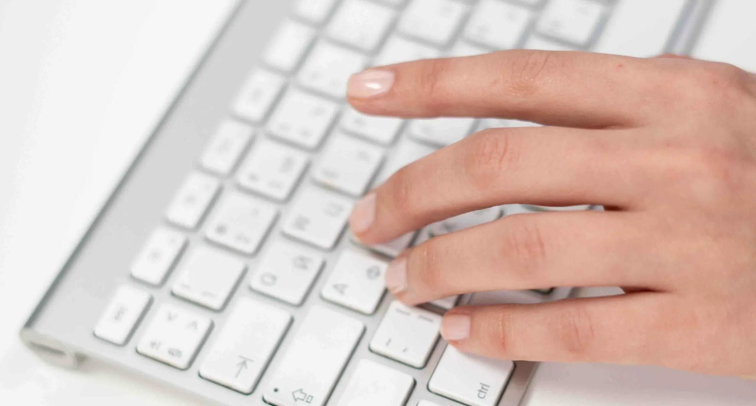 woman's left hand on a top of a white wireless keyboard