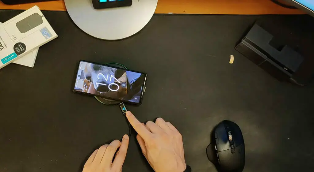 a hand charing Google Pixel 6a phone with a wireless charger