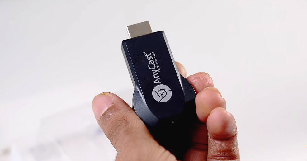 a hand holding an AnyCast device