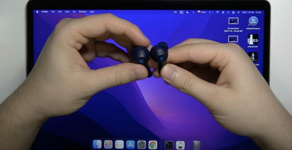 a pair of hand holding a pair of skullcandy earbuds