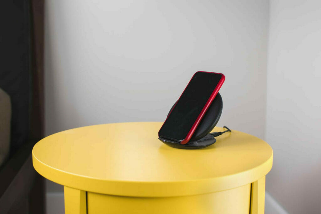 a phone on a wireless charger at the top of a yellow round side table