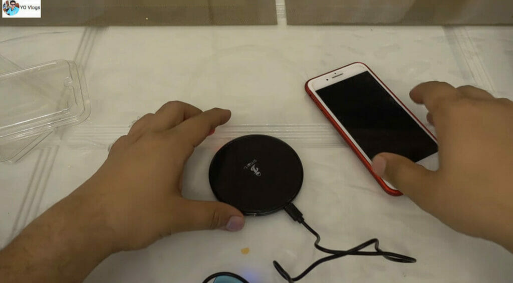 hands reaching out to a wireless charging pad and a phone
