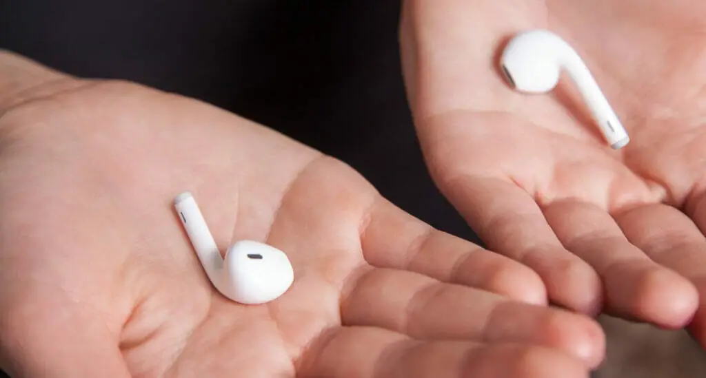 A man's left and right palm open with the white left and right ear bud