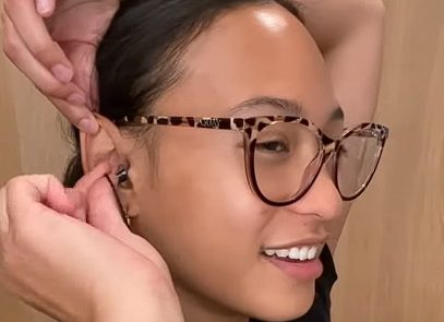 woman in glasses putting her earbud