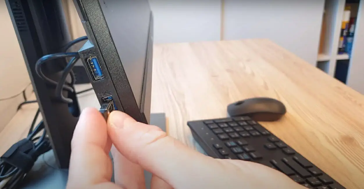 A person connecting the keyboard dongle to the desktop computer