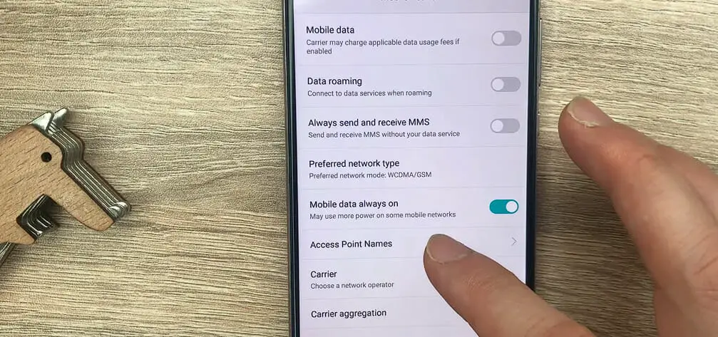 a hand pointing at Access Point Names option on a Samsung phone's setting