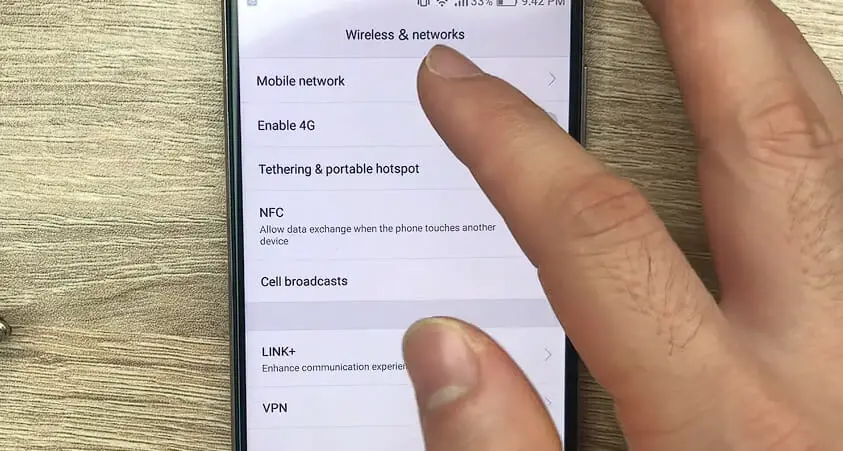 a hand tapping the Mobile Network under Wireless Network option on the phone
