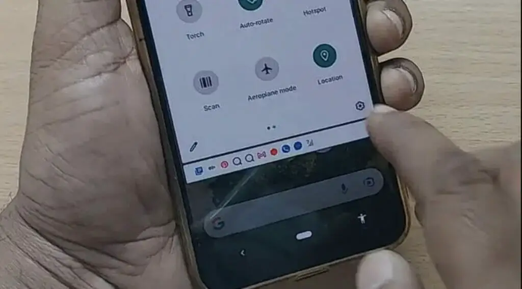 A man holding and tapping the setting button at the bottom right section of the phone