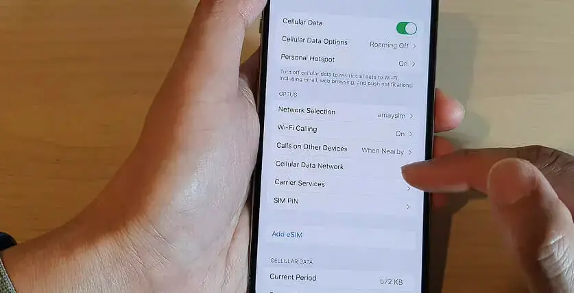 a man's left hand holding up an iphone while the right hand's pointer finger is tapping the Cellular Data Network option