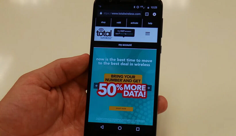 A person holding up a phone with a the total wireless website on it
