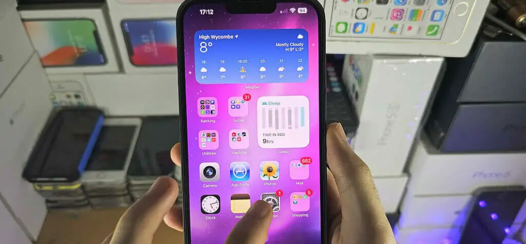 A person holding up a samsung phone and tapping on a setting icon