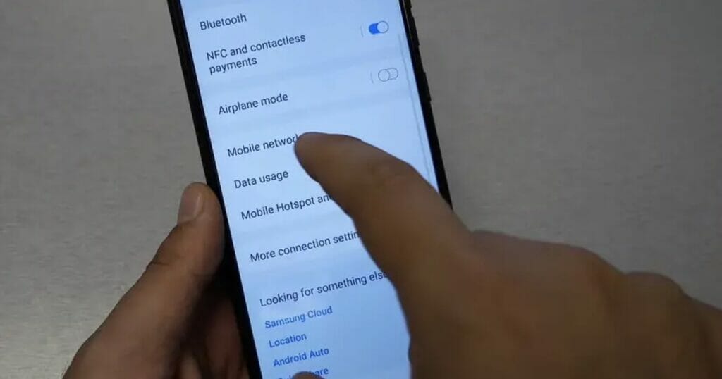 A person tapping on Mobile Network option on Samsung phone setting
