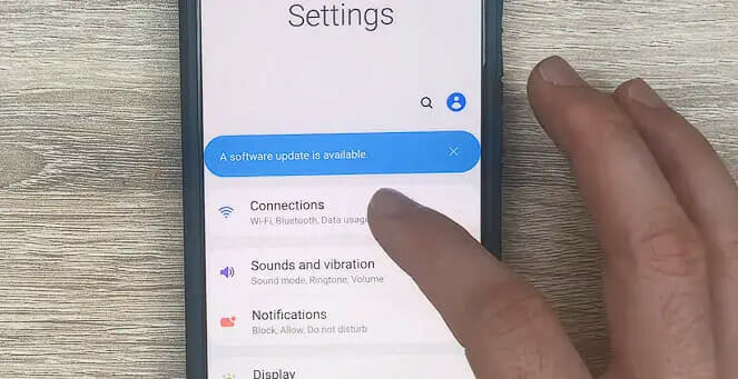 a person's finger tapping the Connections setting on the phone