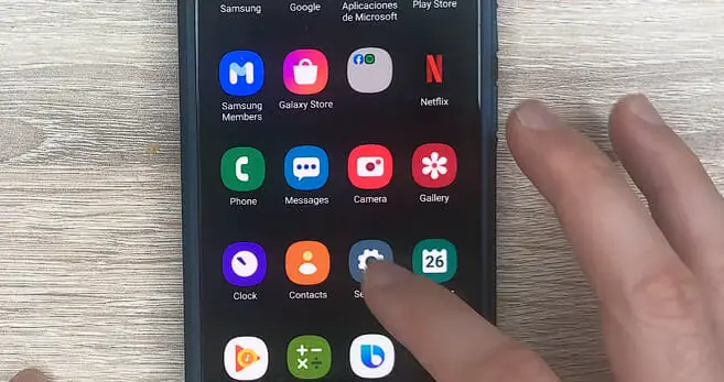 hand tapping on the setting icon from the phone's homescreen