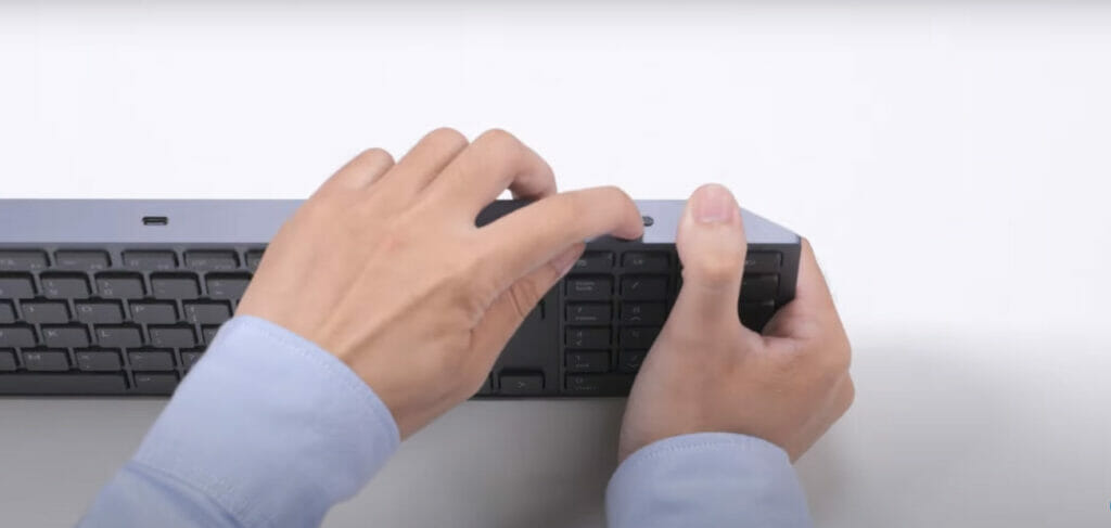 A person turning on a Dell wireless keyboard