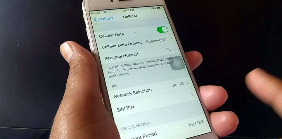 left hand holding a an iphone while right pointer finger enabling the cellular data setting