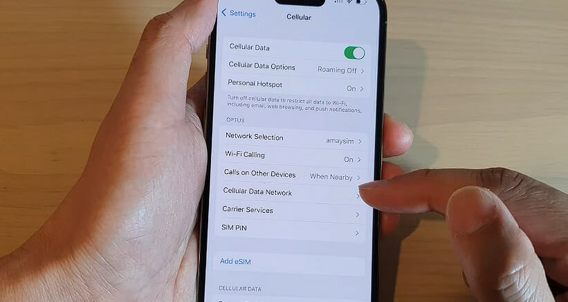 man holding an iphone and tapping the cellular data network option