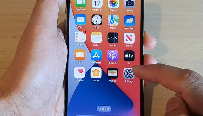 man holding an iphone and tapping the setting icon