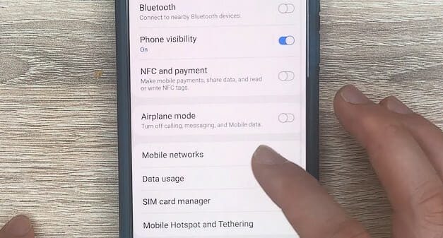 man tapping Mobile networks option on phone setting