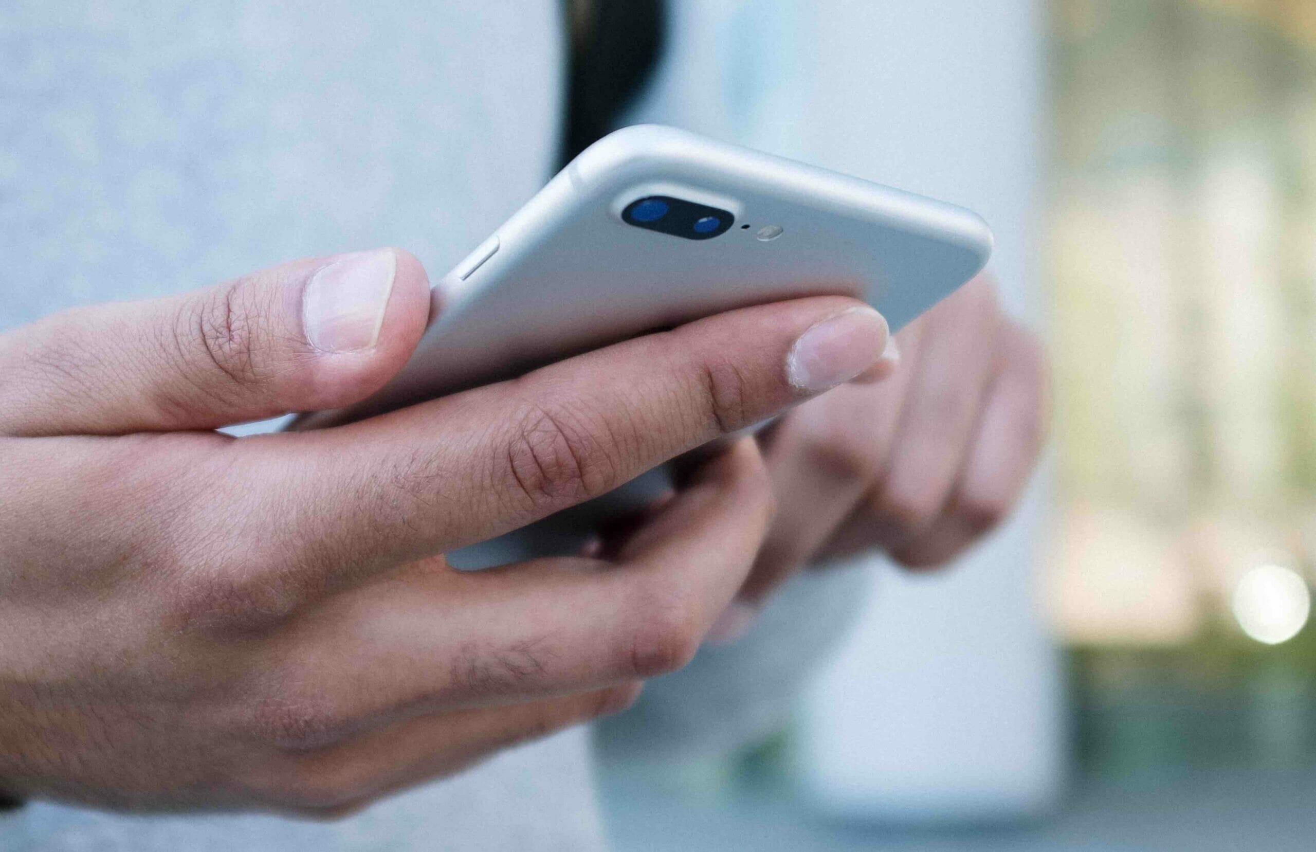 man's hand holding a silver iphone