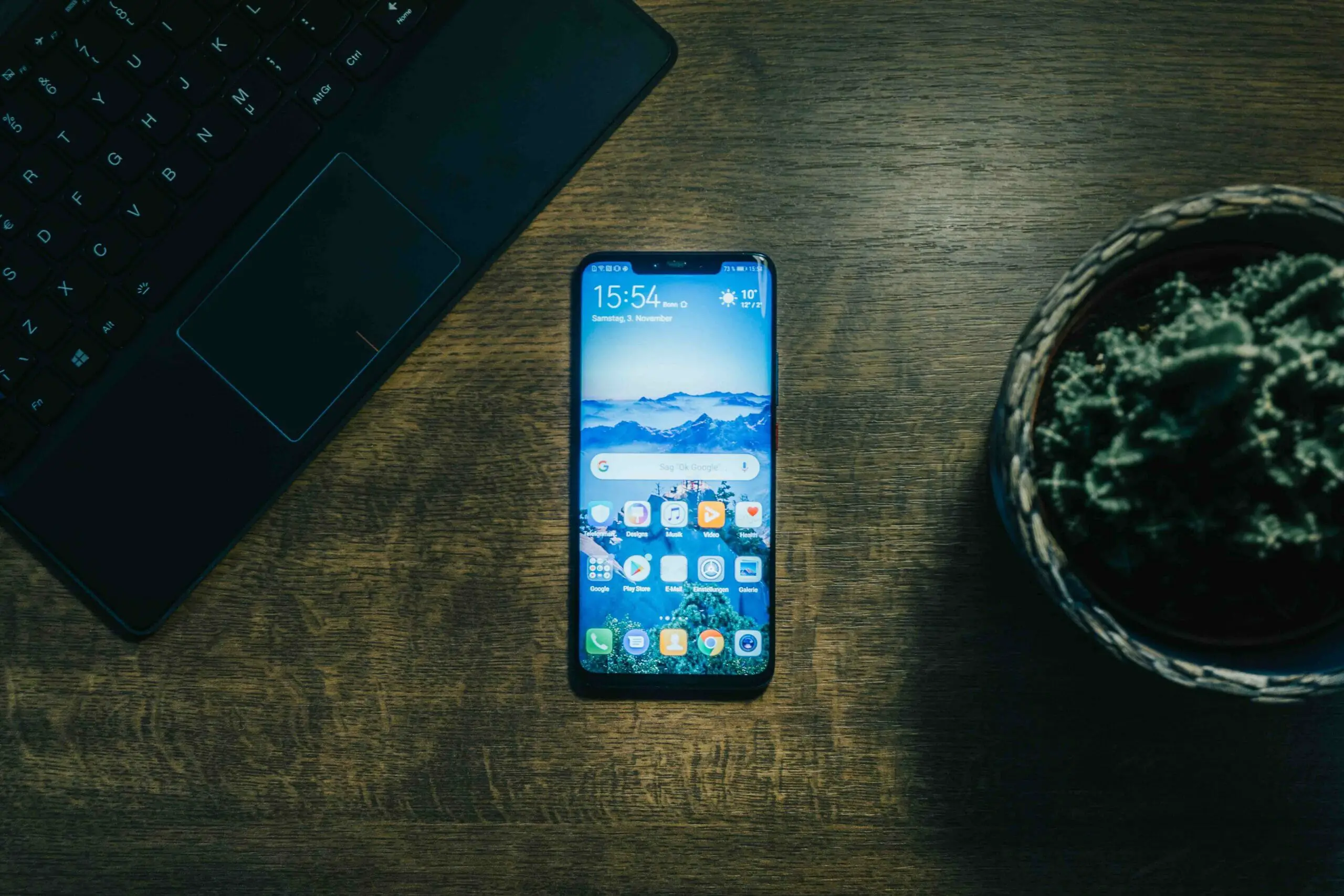 top shot of a laptop, samsung phone, and cactus plant on the table