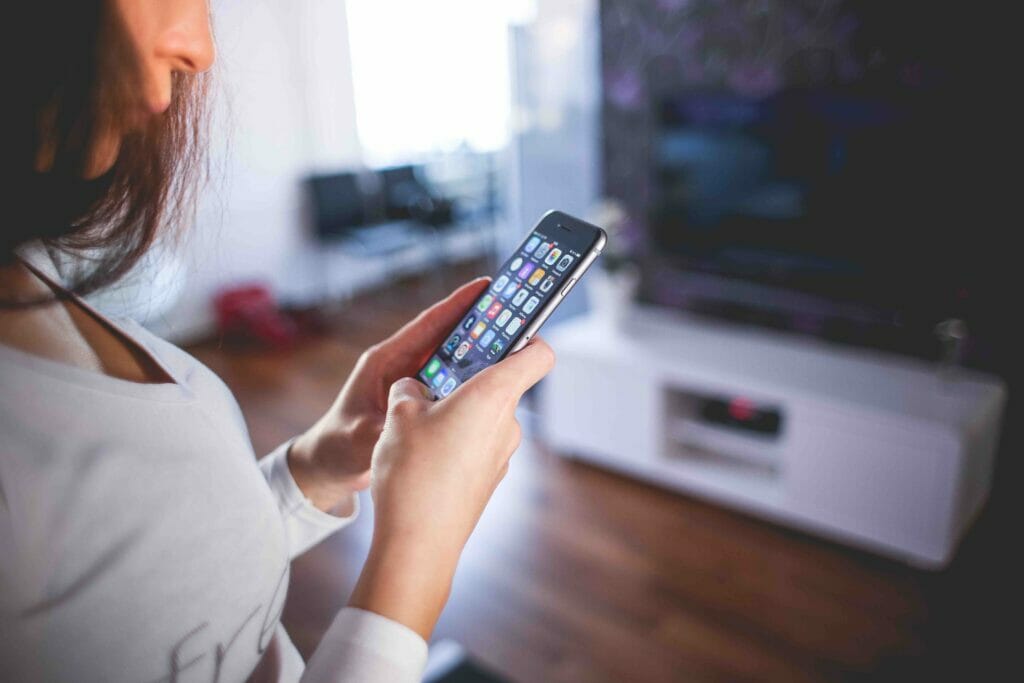 A woman is holding a cell phone in front of a tv