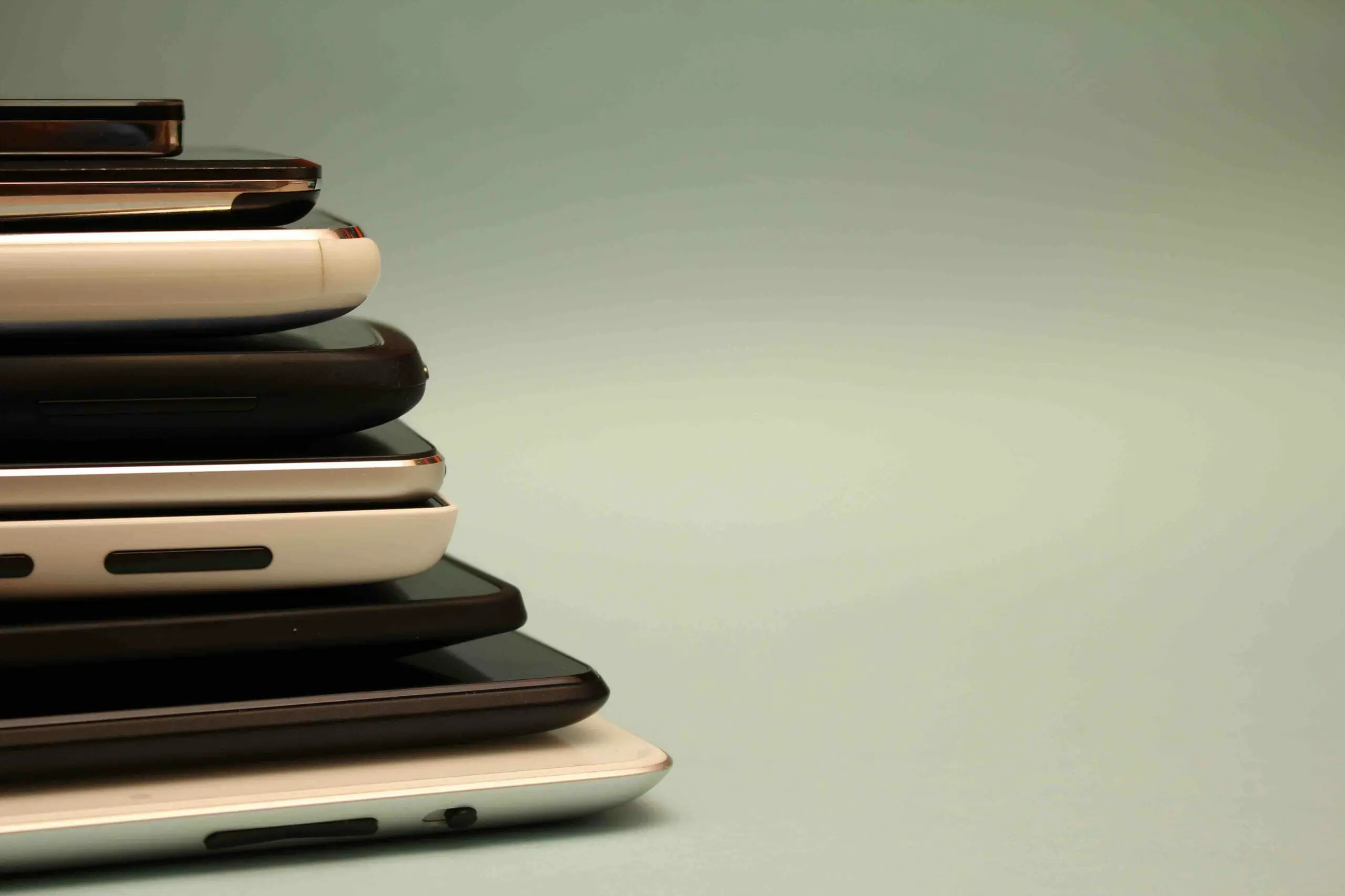 A pile of different phones in a grey-green background