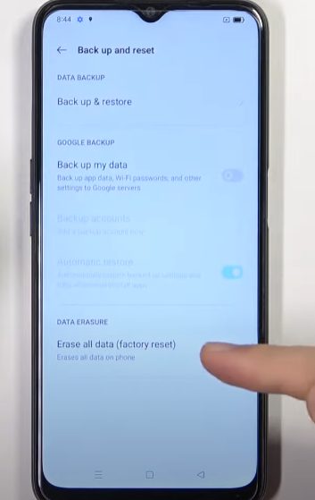 A person tapping on Erase all data option on the phone