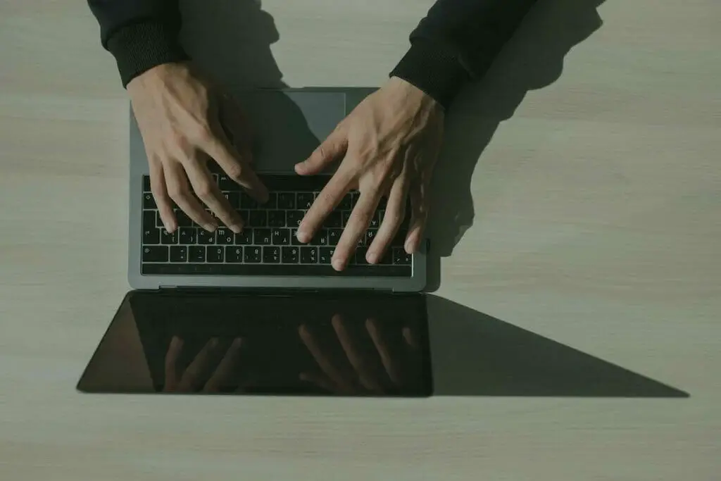 A person's hands typing on a laptop computer