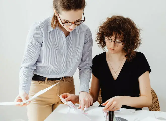 Two women are looking at papers at a desk