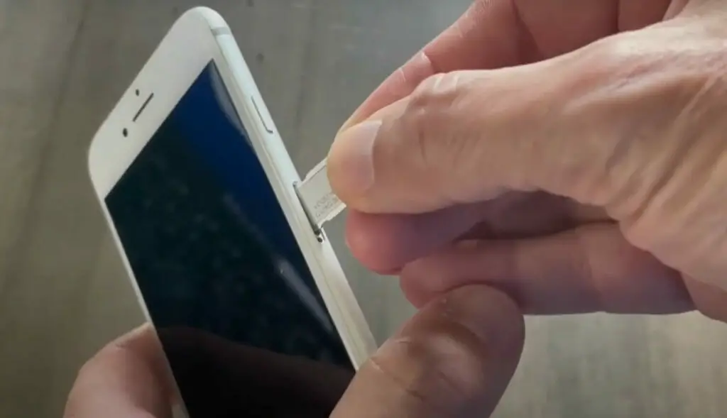 A person inserting a sim card to a white phone