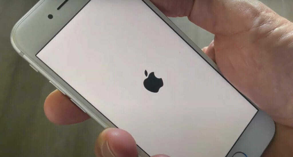 A person turning on his iPhone and a logo of apple shows on the screen