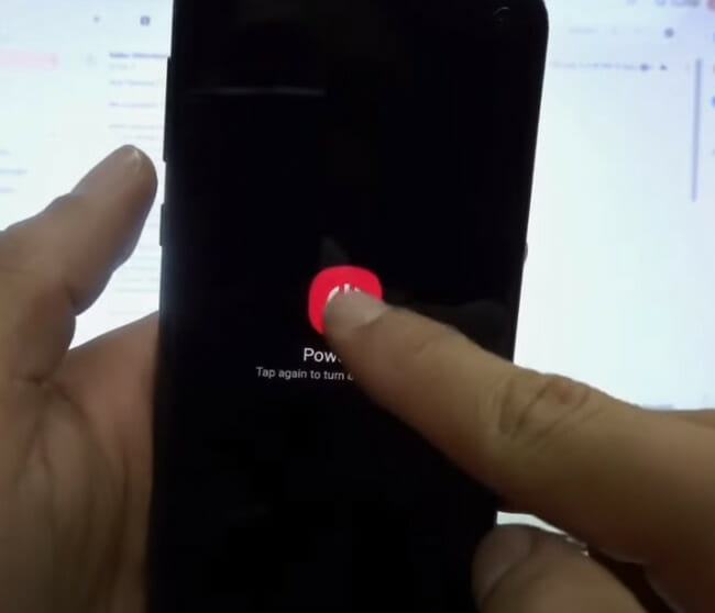 A person is holding a phone and tapping on a power off button