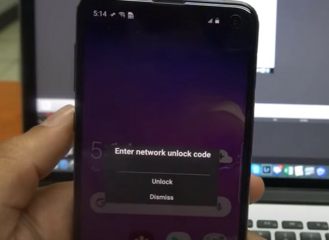A person holding a phone with "Enter network unlock code" text on the screen