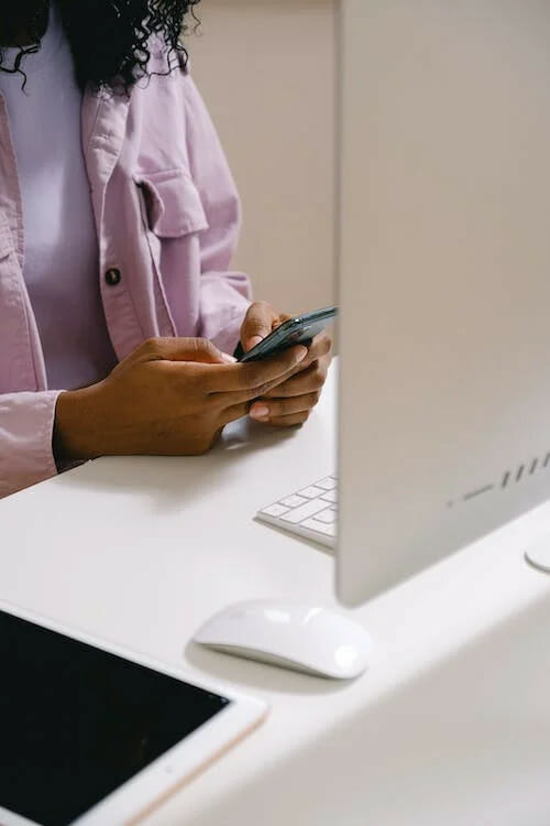 A woman using a cell phone while sitting at a desk