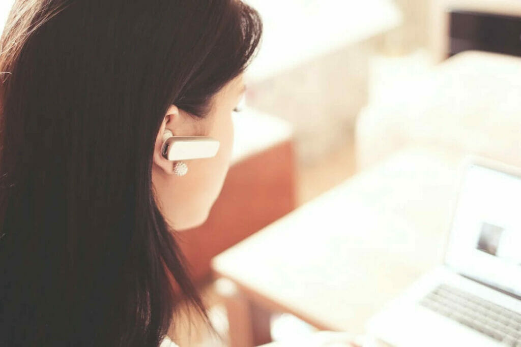 A woman wearing a headset in front of a laptop