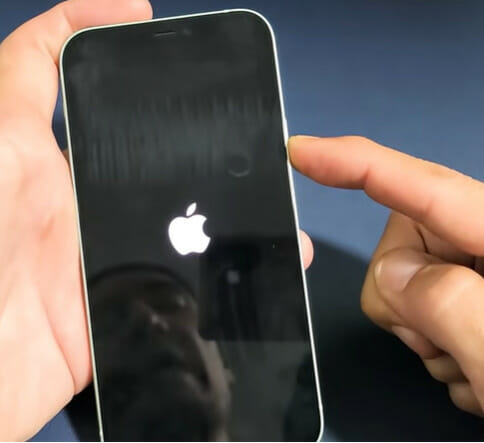 A person is holding up a phone with an apple logo on it