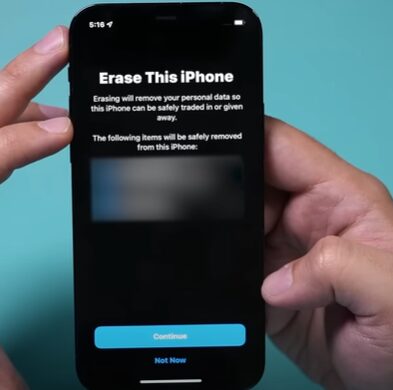 A person is holding up an iphone with an erase this iphone message