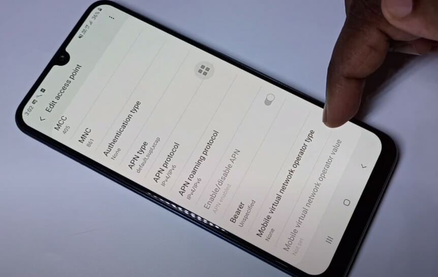 A phone on the table while a person is tapping on the 'Mobile virtual network operator type' option on Access point setting