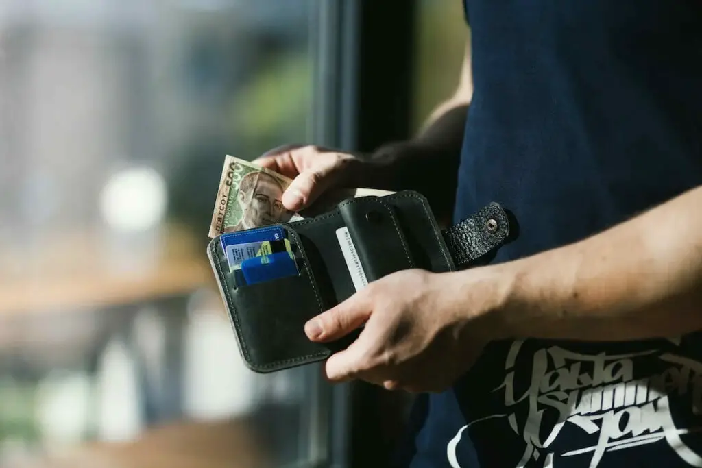 A man is holding a wallet with money in it.
